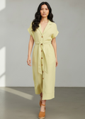 Woman wearing a light yellow dress with buttons in a minimalistic setting