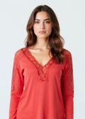 Woman wearing a red lace-trimmed top against a white background