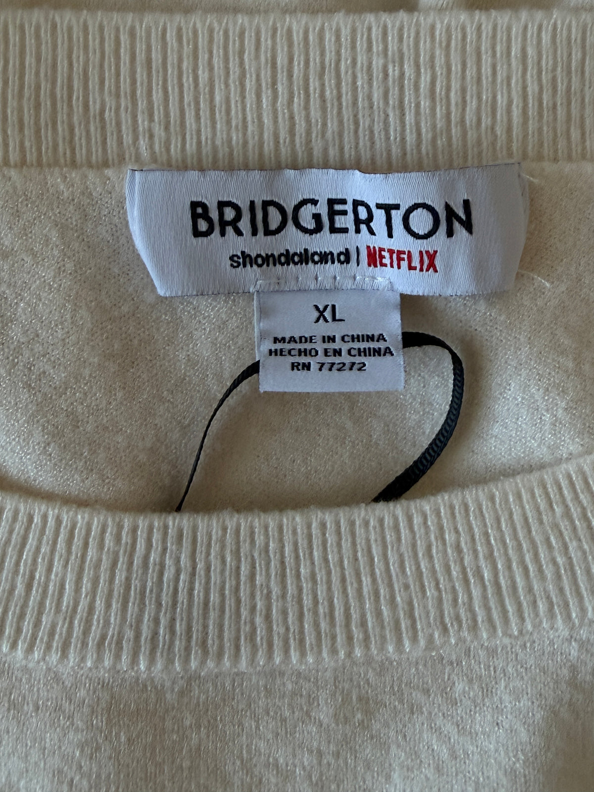 Close-up of a Bridgerton branded tag on a beige fabric background