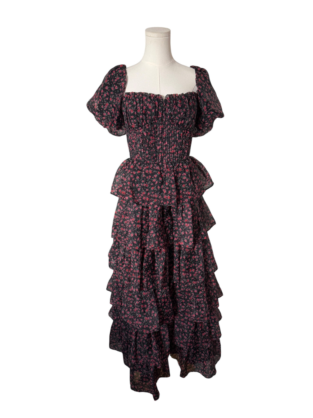 A dark floral midi dress with puff sleeves, a smocked bodice, and a tiered ruffle skirt, displayed on a white mannequin torso against a plain white background.