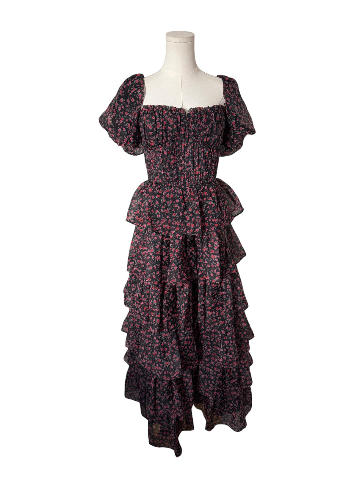 A dark floral midi dress with puff sleeves, a smocked bodice, and a tiered ruffle skirt, displayed on a white mannequin torso against a plain white background.