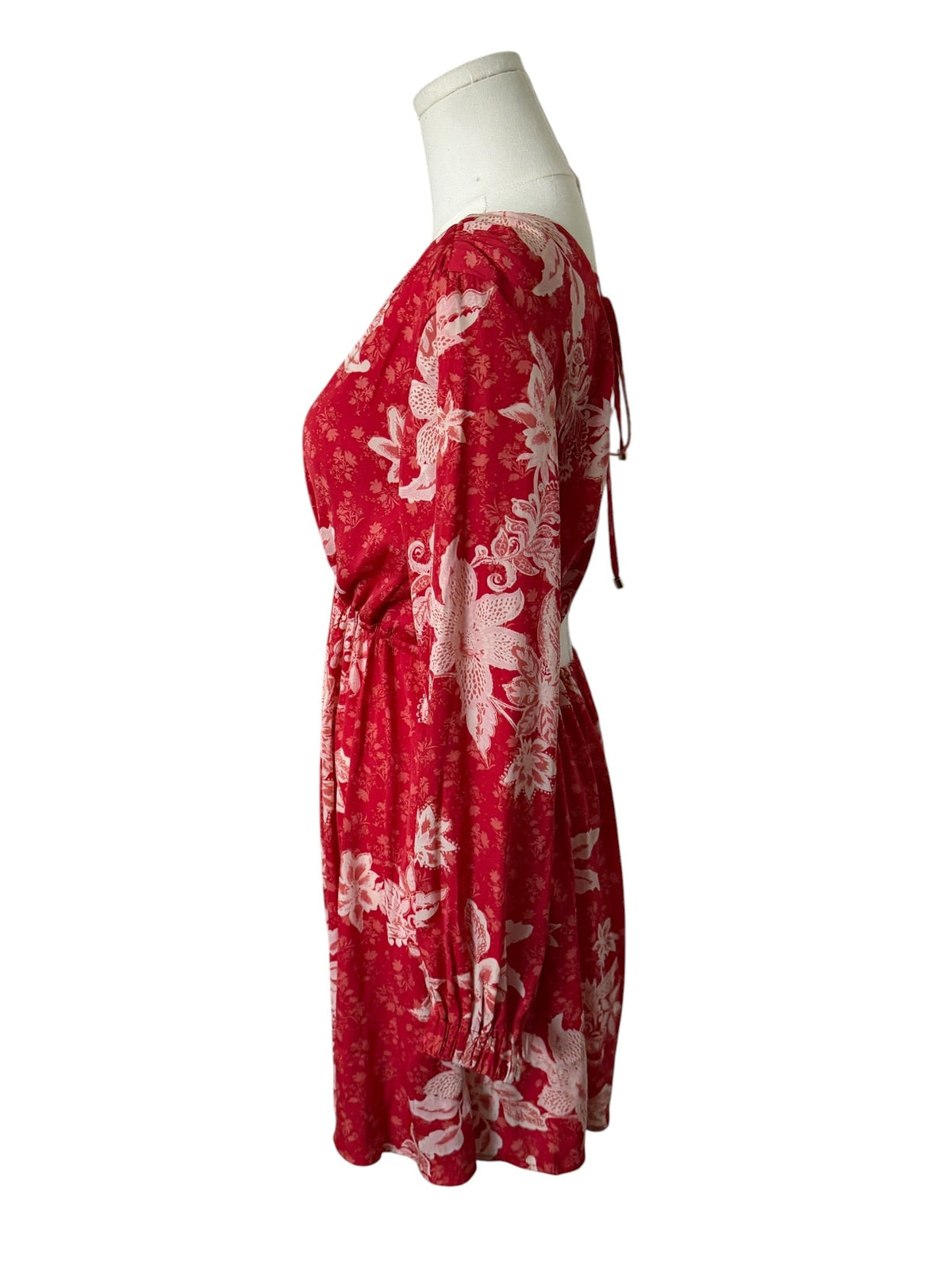 Red dress with white floral pattern on a mannequin against a white background